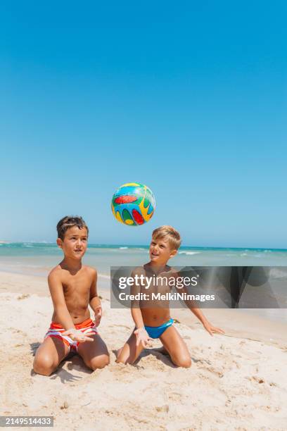 two boys playing football on the beach - kicking sand stock pictures, royalty-free photos & images