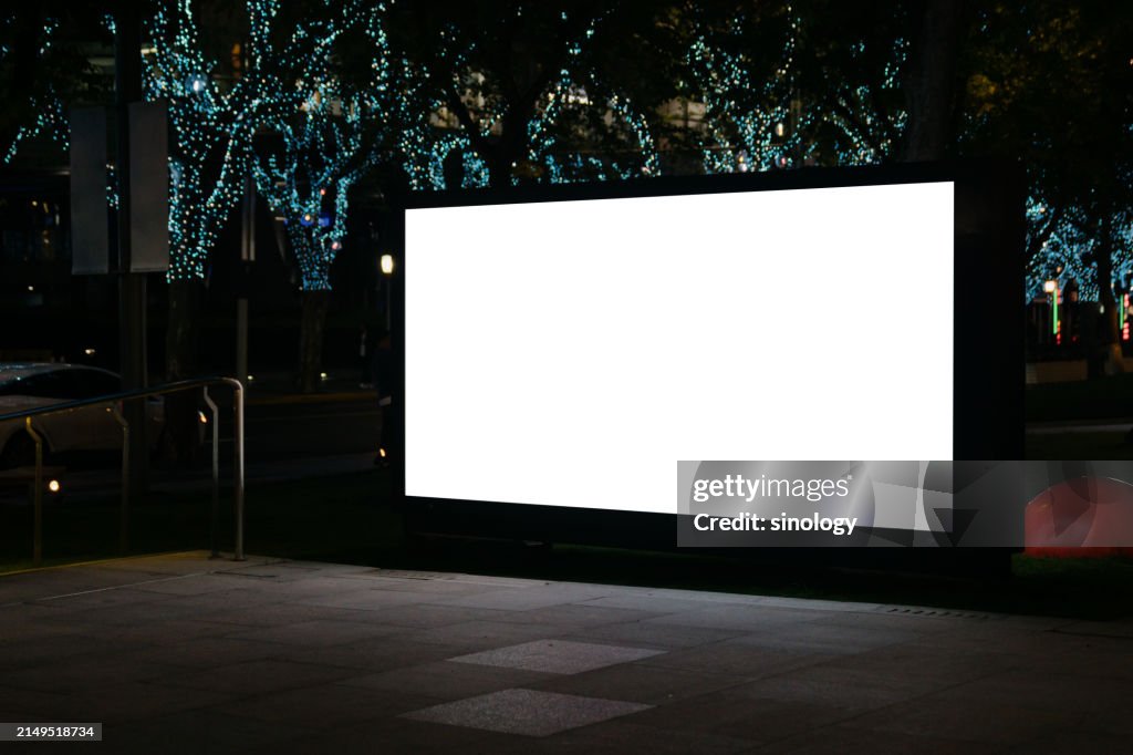Blank billboard on city street at night