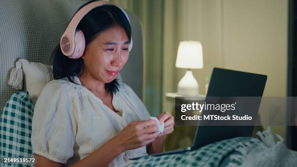 young asian girl media addiction on bed wear headphone cry watch favorite movie in streaming online vod, video on demand in home at night. insomnia, cybersickness, nomophobia, sleep disorder. - crying laughing stock pictures, royalty-free photos & images