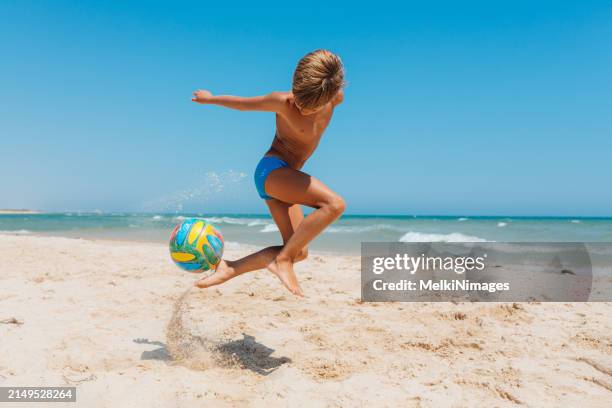 boy having fun with ball at the beach - kicking sand stock pictures, royalty-free photos & images