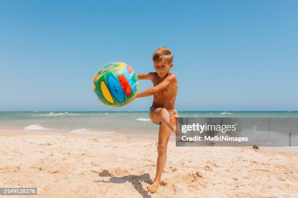 boy having fun with ball at the beach - kicking sand stock pictures, royalty-free photos & images