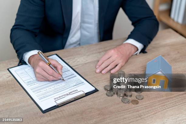 businessman in suit in his office showing home insurance policy - erfenis stockfoto's en -beelden