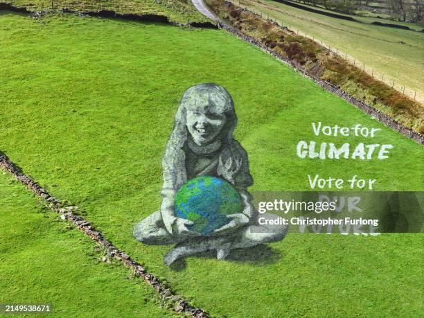 Giant lad art painting by artists Sand In Your Eye of a girl holding the Earth adorns a hill over looking Hebden Bridge on April 19, 2024 in Hebden...
