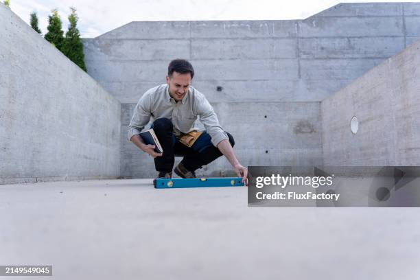 master engineer checking horizontal alignment with a spirit level on a building site - accuracy stock pictures, royalty-free photos & images