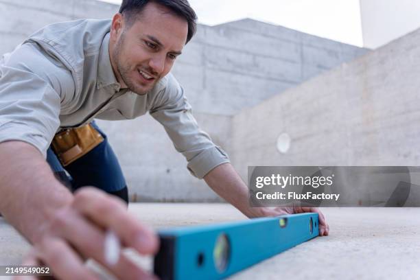 master engineer checking horizontal alignment with a spirit level on a building site - waterpas stockfoto's en -beelden