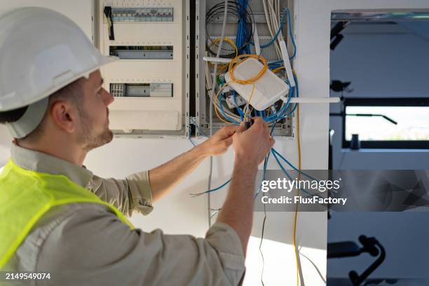 elektriker, der an der elektroinstallation eines neuen hauses arbeitet - bildtechnik stock-fotos und bilder