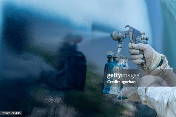 a worker in a body protective suit paints the hull of a sailing yacht with spray. - fibreglass stock pictures, royalty-free photos & images