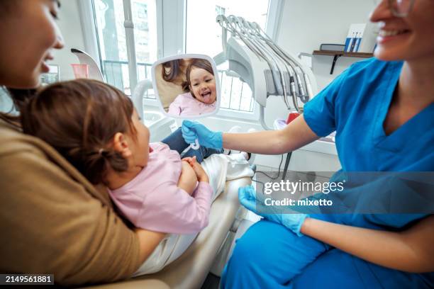 linda niña que se divierte mientras se mira al espejo en el consultorio del dentista - odontopediatría fotografías e imágenes de stock