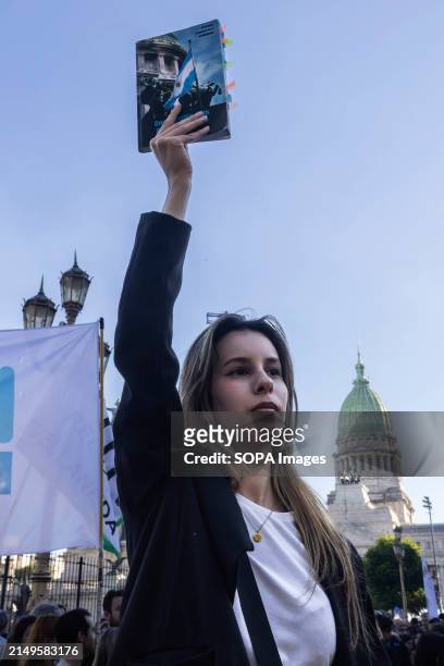 Young woman raises a book according to the slogan proposed in the call for the march. Protesters in favor of public and free education are protesting...