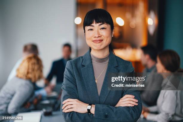 a happy beautiful japanese businesswoman looking at camera while keeping her arms crossed - female leader stock pictures, royalty-free photos & images