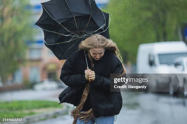 femme blonde sous parapluie. temps de tempête. pluies diluviennes - pluie diluvienne photos et images de collection