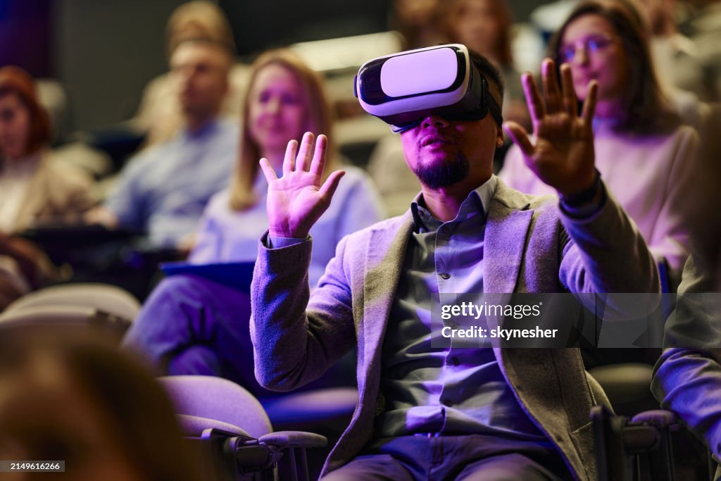 Carefree businessman using VR headset on a seminar in board room.