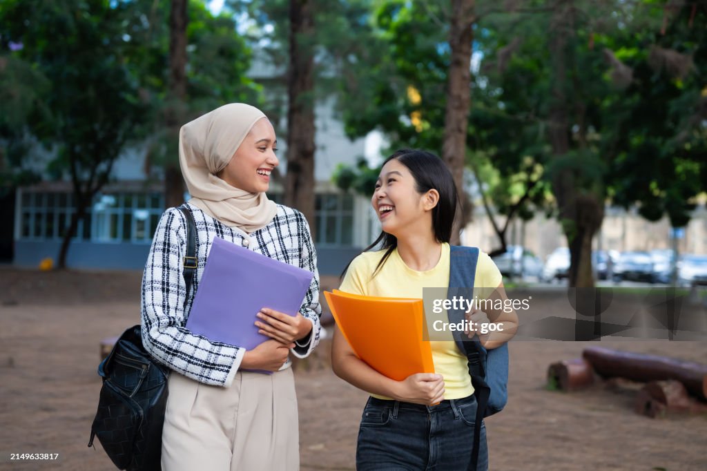 Two diverse young female college students walking together in college campus