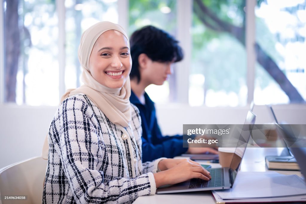 Young female Muslim student with hijab study with laptop in the classroom