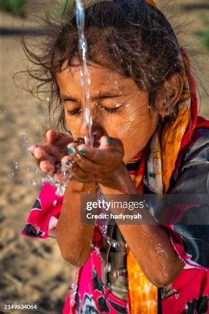 indian little girl drinking fresh water, desert village, rajasthan, india - bohrloch stock-fotos und bilder