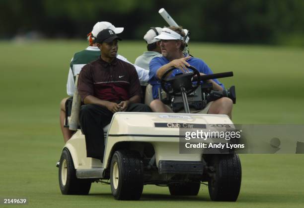 Tiger Woods rides in an ABC camerman's golf cart to leave the course because of a weather delay during the final round of the Western Open on July 6,...