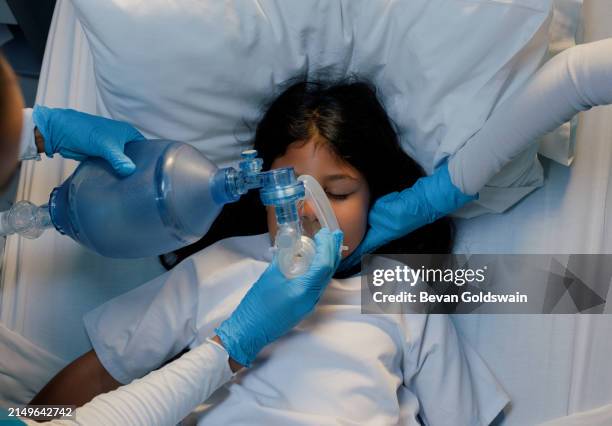 emergency, hospital or oxygen mask for child in bed for icu, help or above life support. breathing, bag and nurse with girl at clinic for cpr, lungs or nebulizer procedure with top view assistance - zuurstof stockfoto's en -beelden