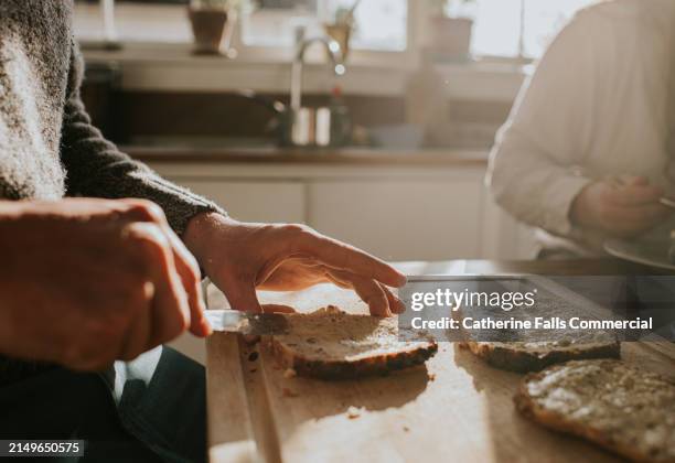 close-up breakfast scene of a man spreading butter on lightly toasted bread - pão imagens e fotografias de stock