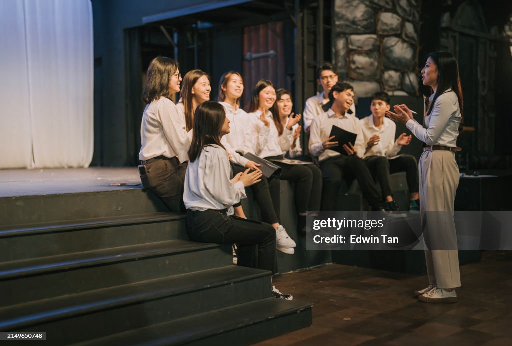Asian Chinese female Choir teacher discussion with choir chorus in stadium stage rehearsal