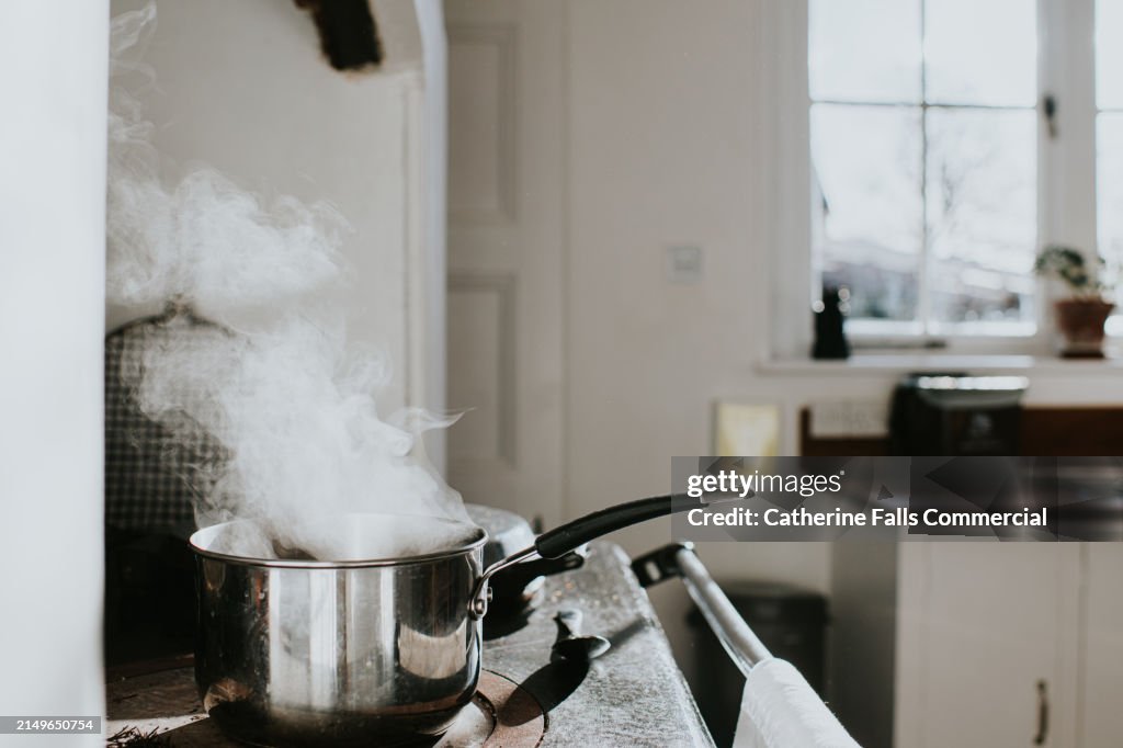 A saucepan full of water boils on a range cooker