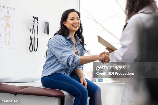 mid adult female patient shakes hands with her new doctor - cuidados de saúde primários imagens e fotografias de stock
