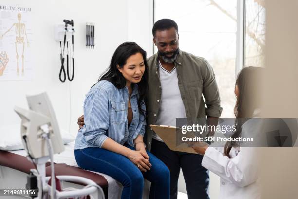 una doctora irreconocible habla con la pareja en la clínica - fecundación in vitro fotografías e imágenes de stock