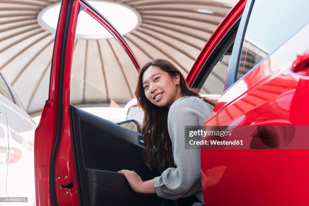 Smiling woman disembarking from red car