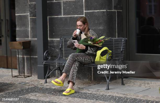 Sonia Lyson seen wearing black sunglasses, grey faded vintage oversized bomber leather jacket, beige / brown leopard print pattern jeans pants, lime...
