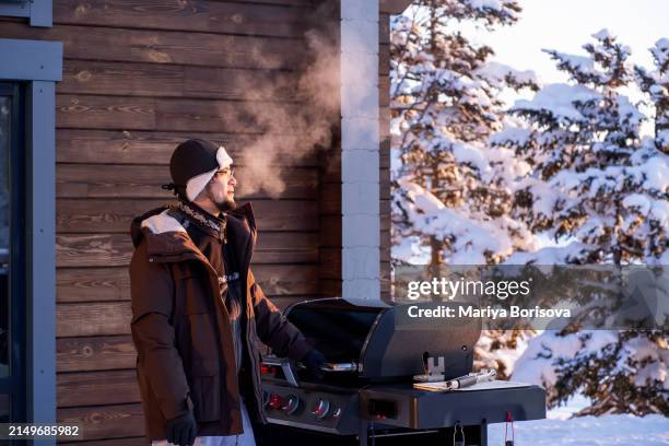 a man cooks on a grill on the veranda of a large house in winter. - bbq winter ストックフォトと画像