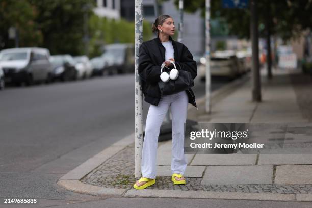 Sophia Geiss seen wearing silver earrings, light grey cropped top, matching light grey wide leg pants, black oversized bomber jacket, black leather...