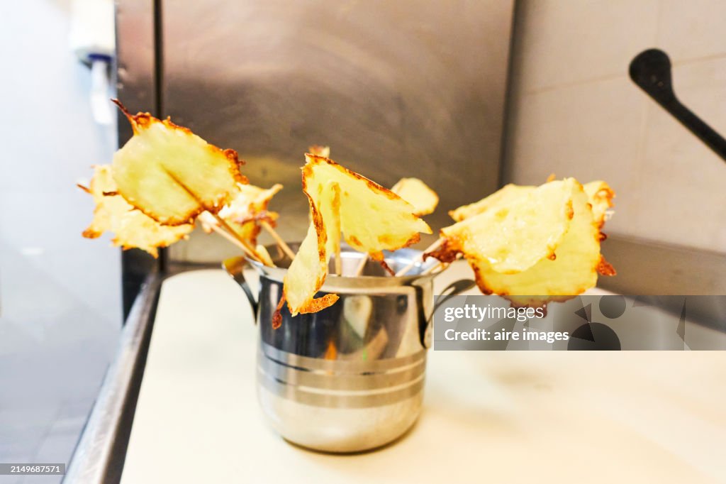Front view of some fried chips with toothpicks inside a glass jar without people around