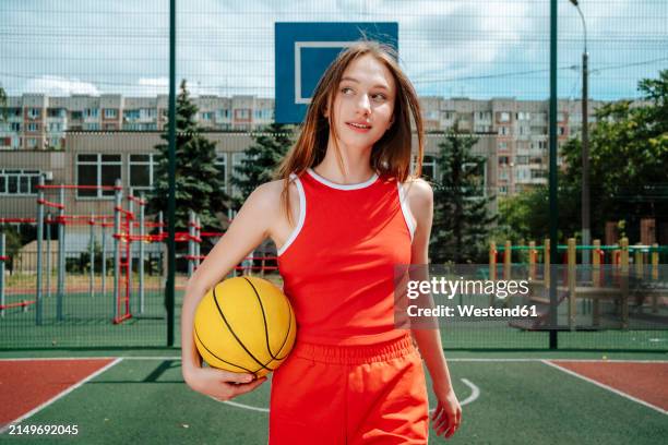 basketball player carrying ball under the arm and walking in school yard - basketball uniform stock pictures, royalty-free photos & images