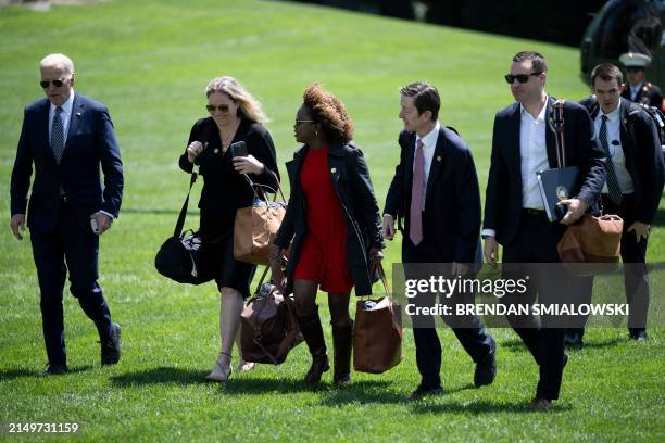 Staff walk alongside US President Joe Biden as they walk from Marine One to the residence of the White House in Washington, DC, on April 26 after...