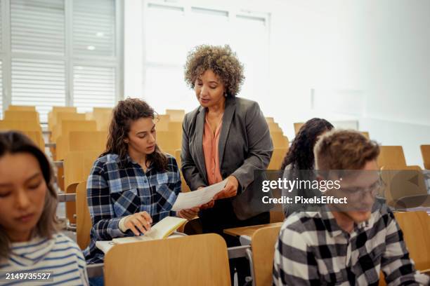 reife lehrerin gibt ihrem schüler prüfungsarbeit - professor stock-fotos und bilder