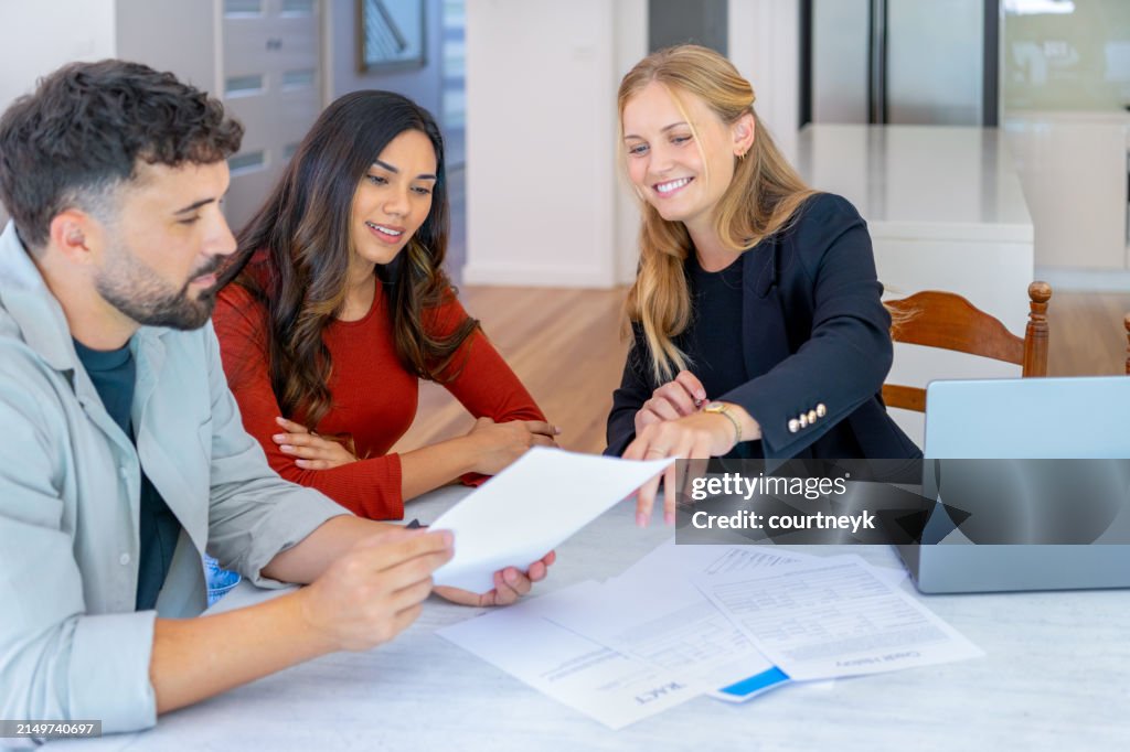Real Estate or Insurance agent with couple looking through documents.