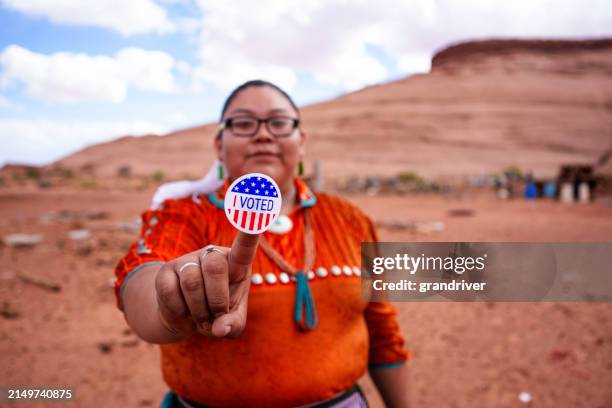 junge navajo-frau in ihren zwanzigern im monument valley tribal park, arizona, hält einen "i vote"-aufkleber in der hand, um ihre bürgerpflicht zu erfüllen - apache stock-fotos und bilder