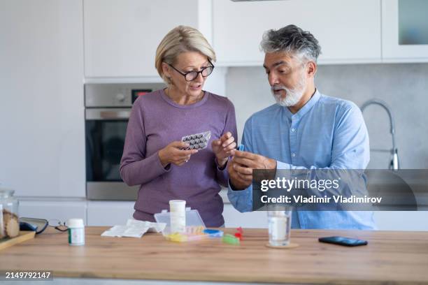 senior couple are organizing their medication into a pill box - pill organizer stock pictures, royalty-free photos & images