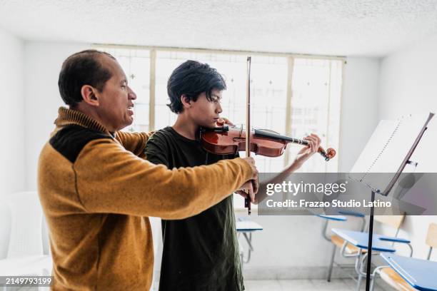 instructor teaching boy to play violin at class - violin lesson stock pictures, royalty-free photos & images