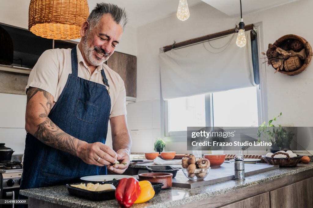 Mature man preparing homemade pasta dough in the kitchen for selling at home