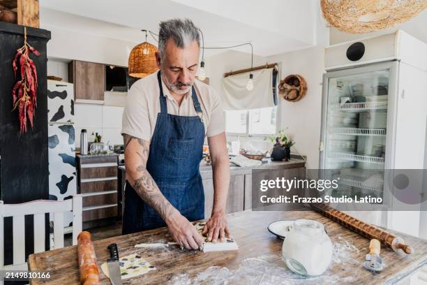 reifer mann, der hausgemachte ravioli für den verkauf zu hause zubereitet - selbständige erwerbstätigkeit stock-fotos und bilder