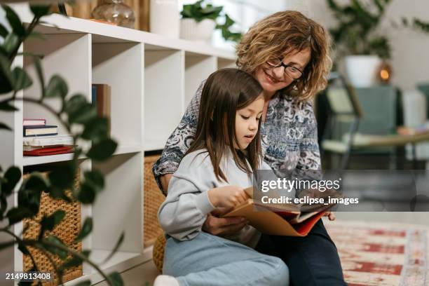 grandma is reading a book to her grandson - 60 64 years stock pictures, royalty-free photos & images