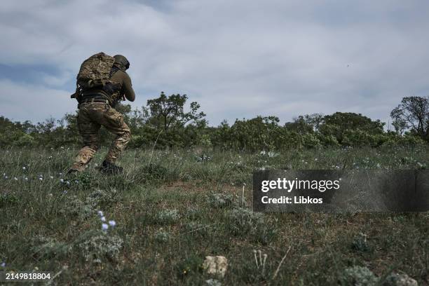 Ukrainian infantrymen from the 126th Territorial Defense Brigade train on land moving through the bush after landing from boats in training to carry...