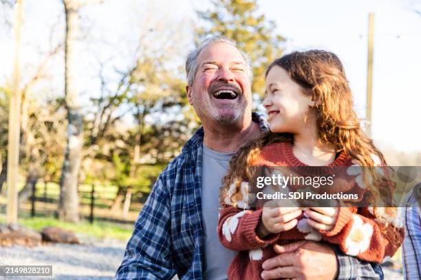 elementary age girl tells grandfather funny story - granddaughter stock pictures, royalty-free photos & images