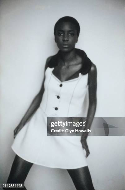 Fashion model is posed in a studio wearing a skirt and sleeveless jacket, circa 1992.