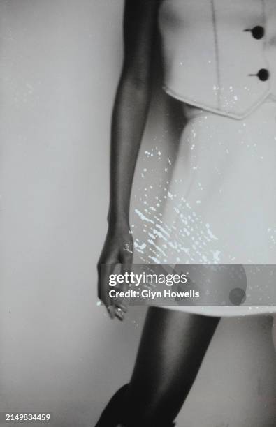 Fashion model is posed in a studio wearing a skirt and sleeveless jacket, circa 1992.