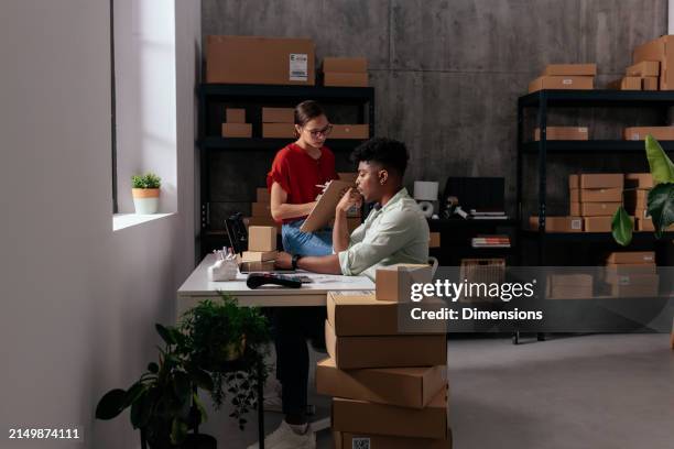 two colleagues at a desk with boxes in the warehouse - one woman two men stock pictures, royalty-free photos & images