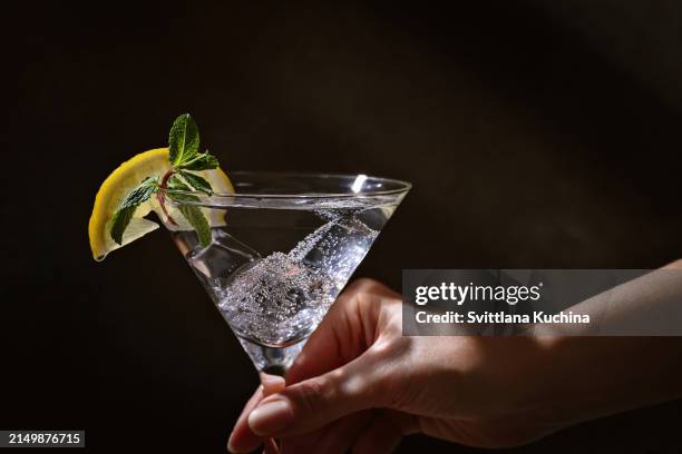 woman holding martini with lemon - alkoholfrei stock-fotos und bilder