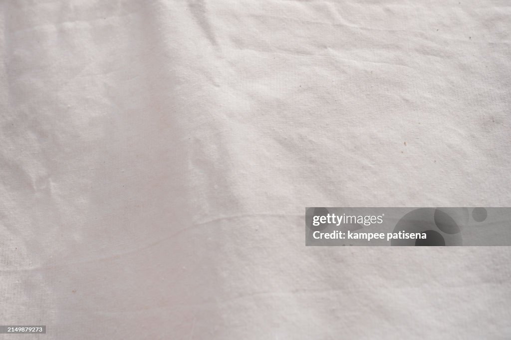 A whtie fabric with a pattern of lines and dots. The fabric is soft and smooth to the touch