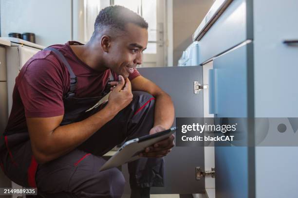 african american handyman using digital tablet at customer's home - looking under sink stock pictures, royalty-free photos & images