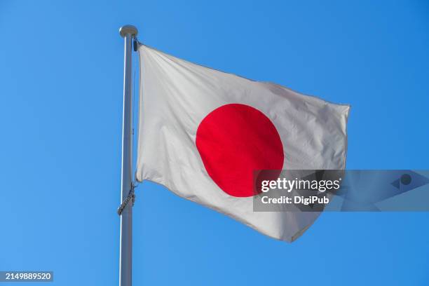 pride and tradition: the japanese flag against a clear blue sky - japanische flagge stock-fotos und bilder